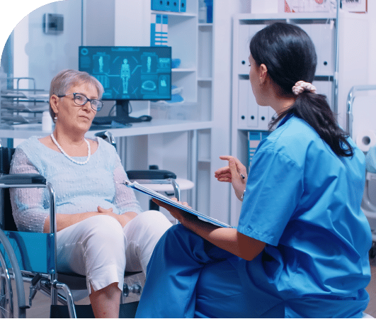 Doctor talking to older female patient in wheelchair