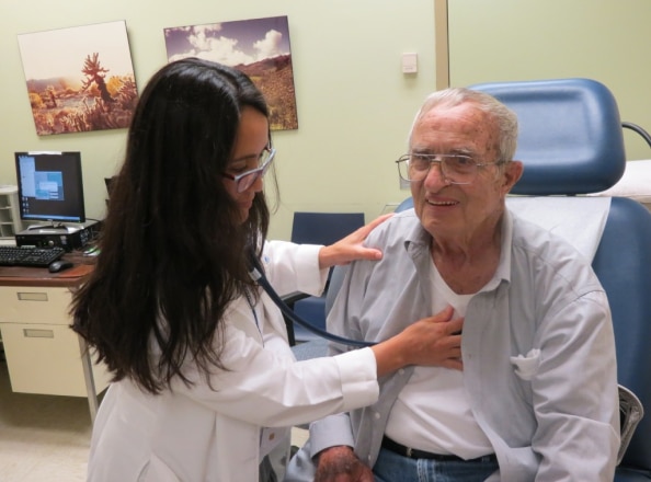 Younger female doctor checking vitals of older man
