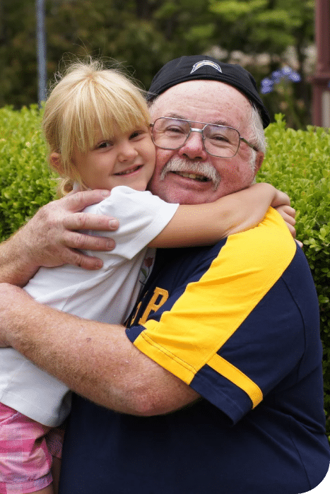 a young girl hugging a elderly man