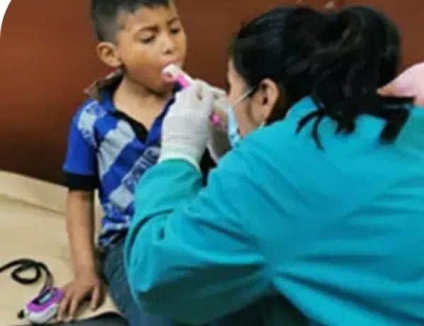 woman wearing personal protective equipment treating young male child