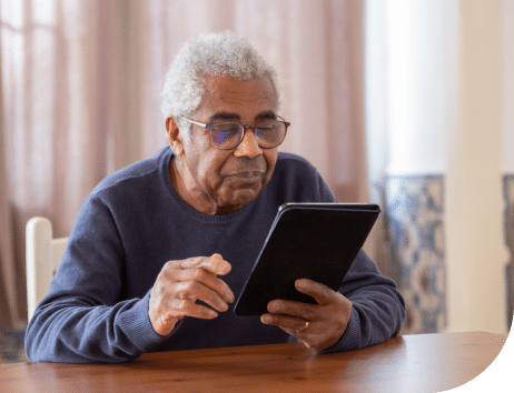 Elderly man looking at a tablet while sitting.