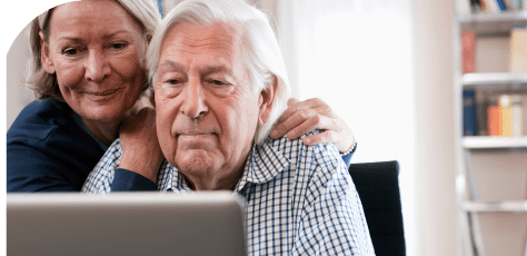An elderly couple sitting together, looking at a laptop, reviewing information on mesothelioma and its impact on seniors.