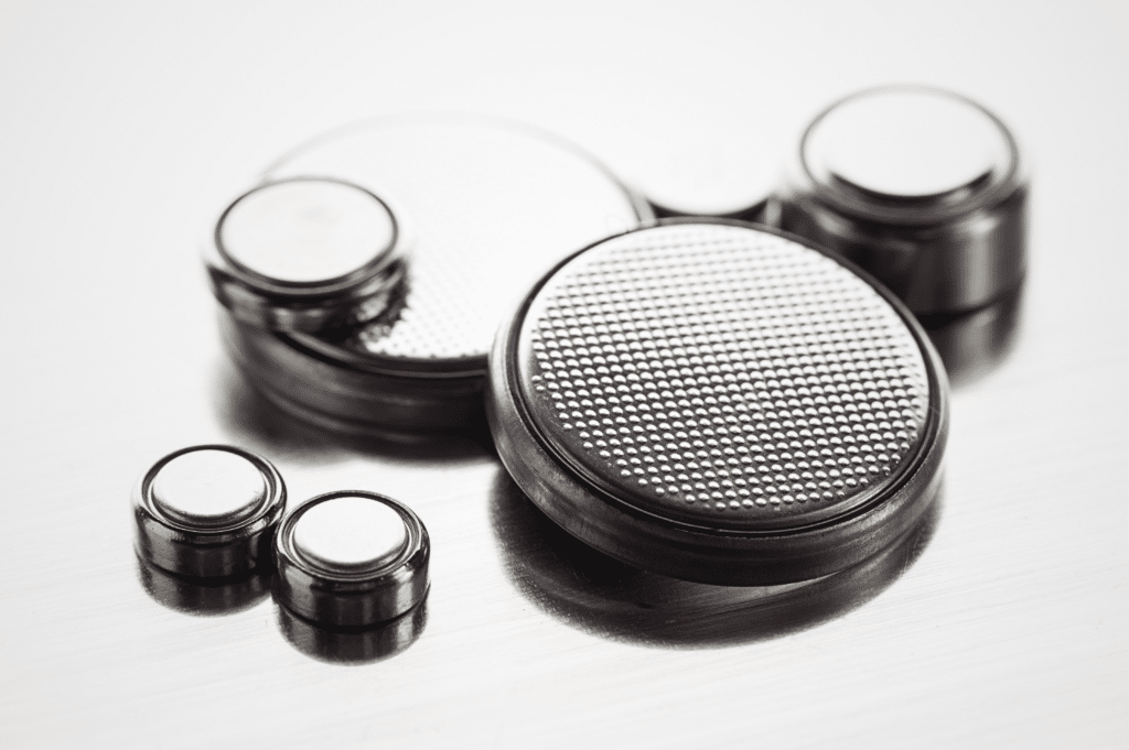 Various sizes of button batteries arranged next to each other on a white surface.