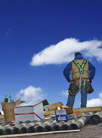 Worker on a roof with building materials and a clear sky