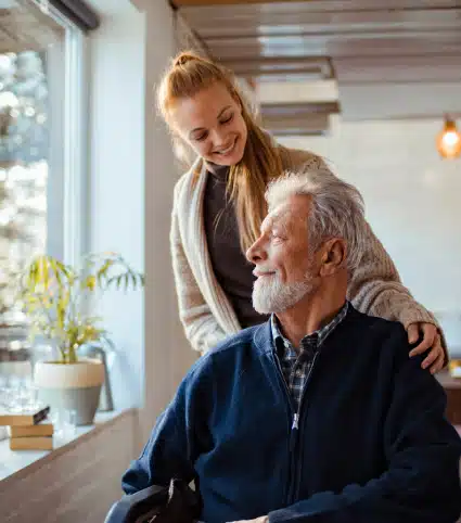 Male mesothelioma patient in a wheelchair feeling comforted by a caregiver and looking out a window