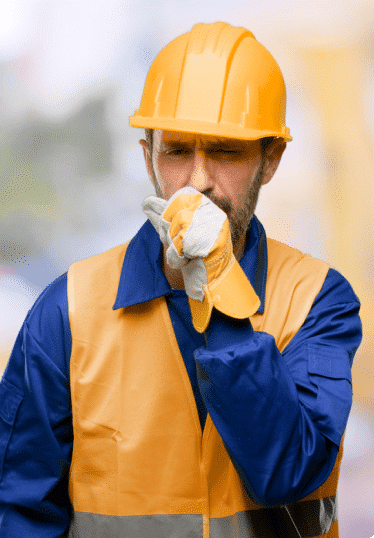 Worker wearing protective equipment and covering his mouth while coughing