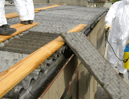 Workers with protective equipment removing asbestos roof shingles