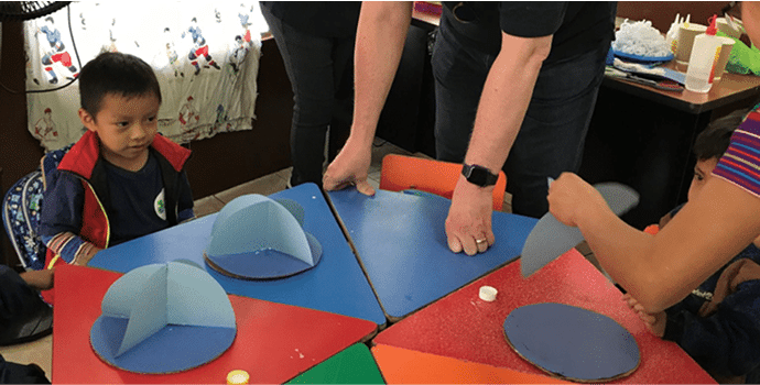 A child and a teacher at a table with an interactive activity