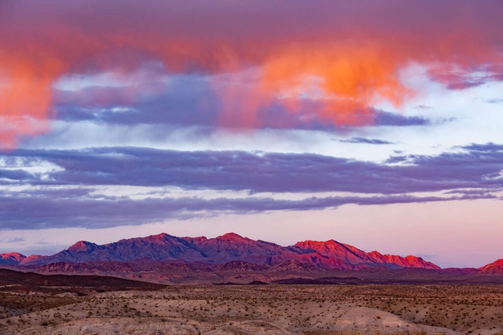 Orange sunset clouds over barren arid mountain desert landscape near Lake Mead by Las Vegas, Nevada
