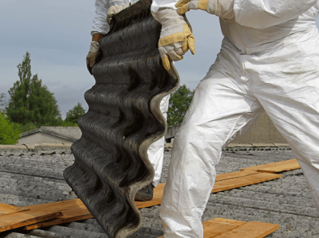 Workers with protective equipment removing asbestos from a roof