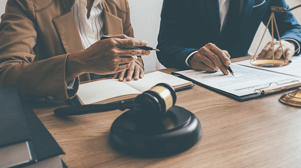 two sets of hands over paperwork - lawyer showing client where to sign