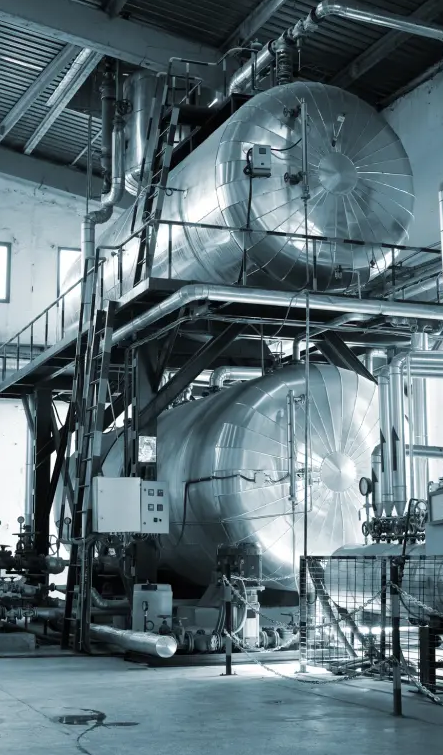 Two old boilers in black and white, one on top of the other