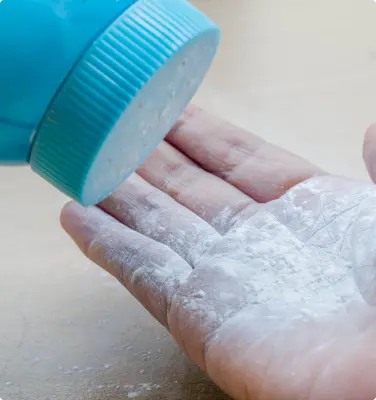 Baby powder being poured from blue bottle to a hand