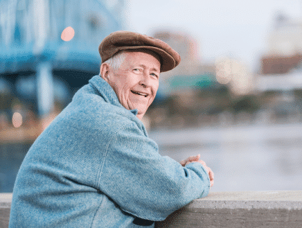 Veteran with mesothelioma and a blue sweater smiling at the person holding the camera