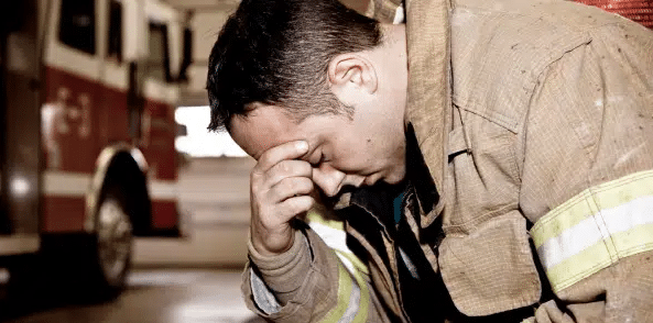 Firefighter with his head resting on his hand after being exposed to asbestos