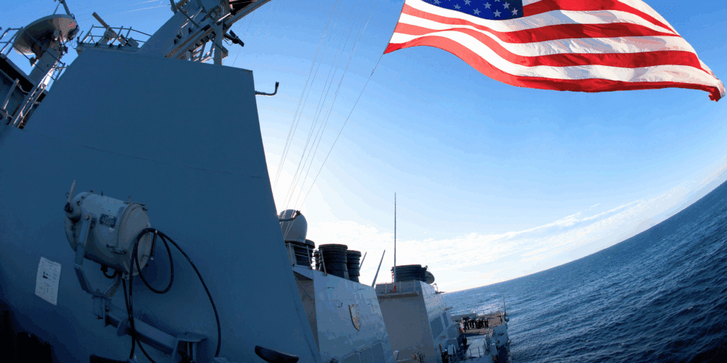 U.S. Navy ship view from high deck with the ocean and the American flag waving