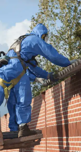 People wearing protective equipment removing asbestos from the roof of a house