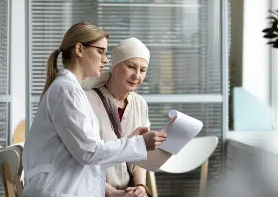 Doctor explaining medical prognosis to woman with cancer, seated and wearing a head scarf