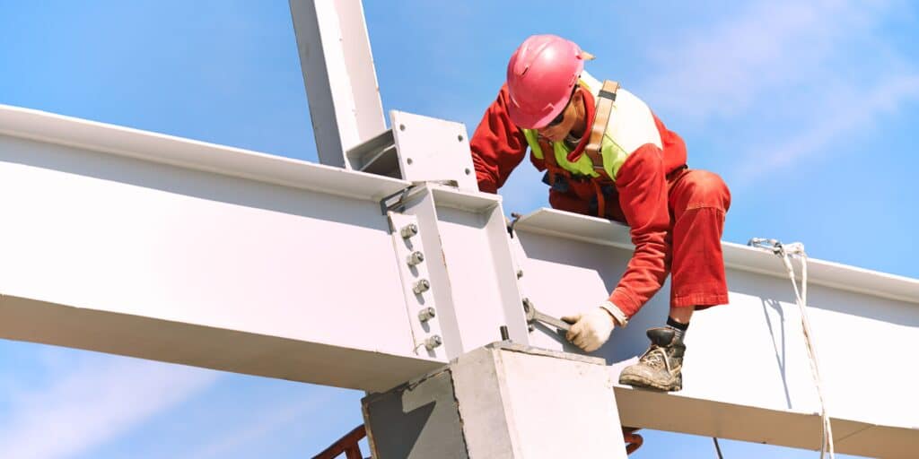 Millwright working high up on the maintenance of a factory beams