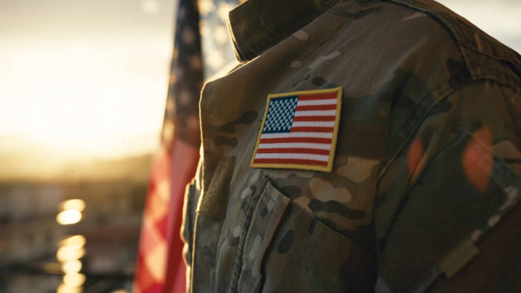 An army veteran with a close up on the uniform and American flag representing individuals exposed to asbestos during service.