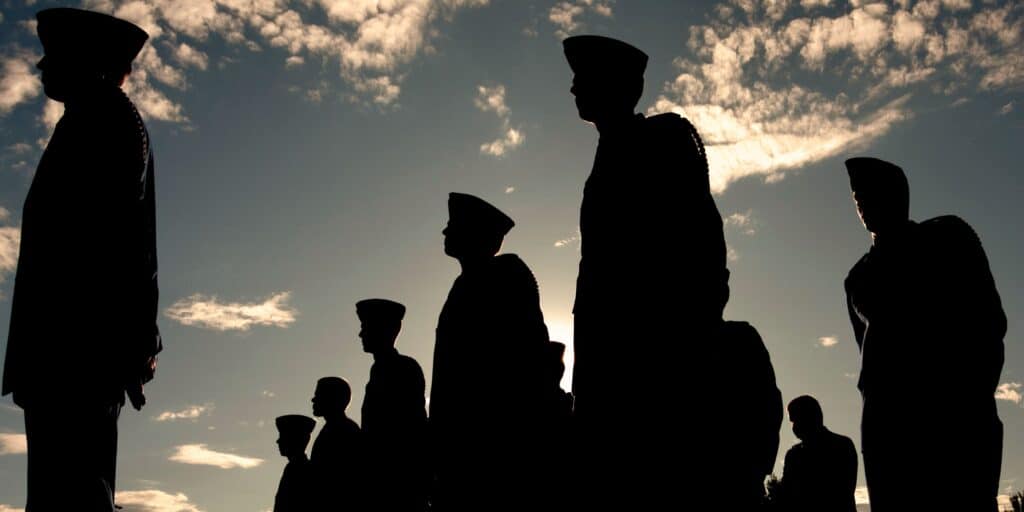Black silhouette of U.S military personnel with the sun setting in the back, representing compensation for service