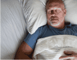 Adult sleeping in bed with white sheets