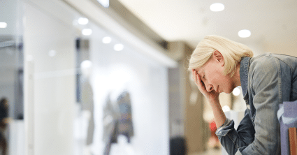 Woman sitting down, tired, and holding her head