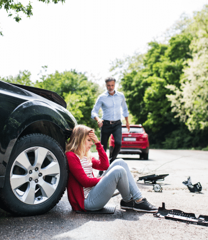 Woman overwhelmed after car accident and man walking toward her