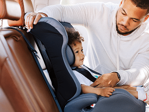 Dad fastening seat belts on child's car seat