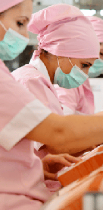 Three female factory workers dressed in pink work clothes