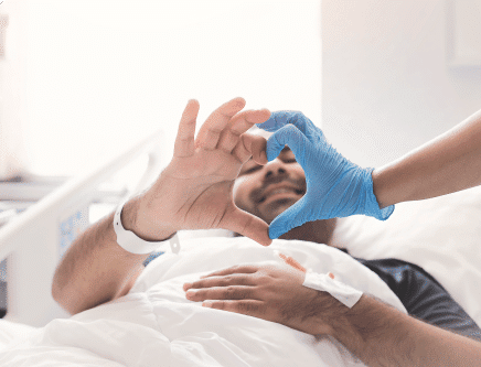 Young male patient getting chemotherapy and making a heart shape with his hand and the hand of the doctor