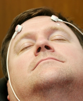 Person with eyes closed and electrodes attached to their head
