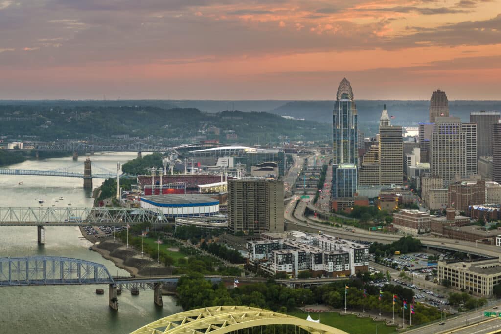 Cincinnati city in state of Ohio with brightly illuminated high skyscraper buildings in downtown district. American megapolis with business financial district at sunset.