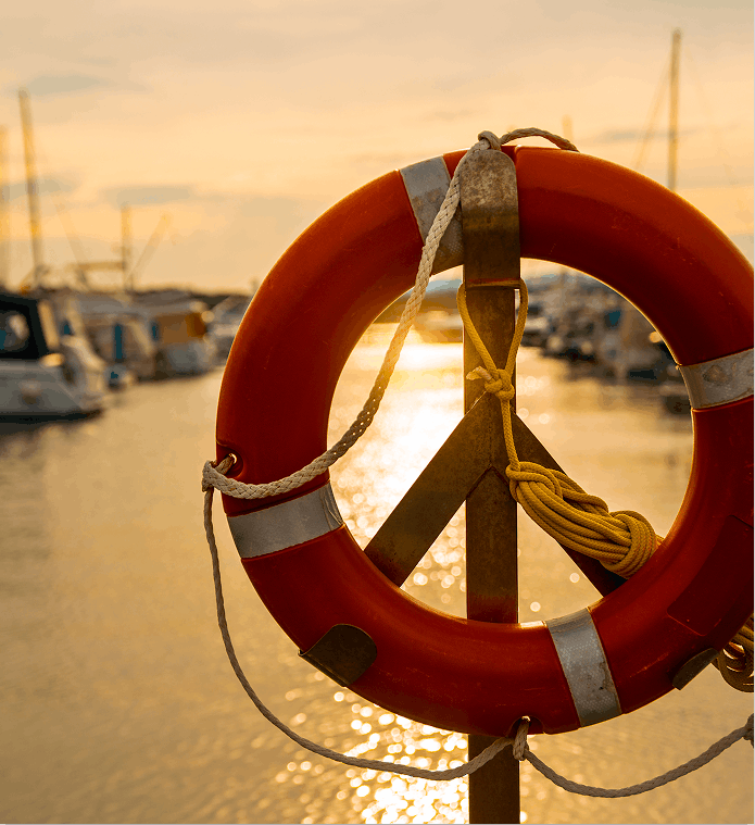 A lifebuoy at sunset with the bay behind it