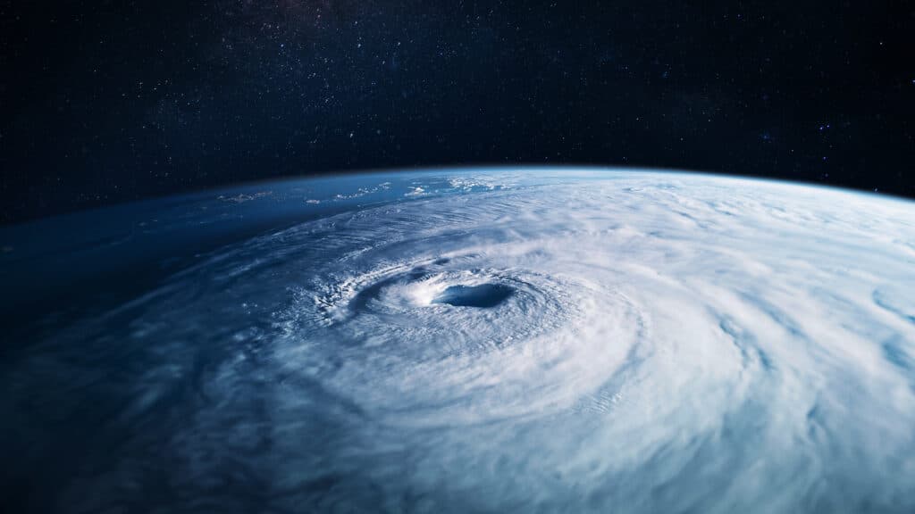 An image of a large hurricane viewed from space, with a background of a dark, starry sky. The earth curves in the distance.